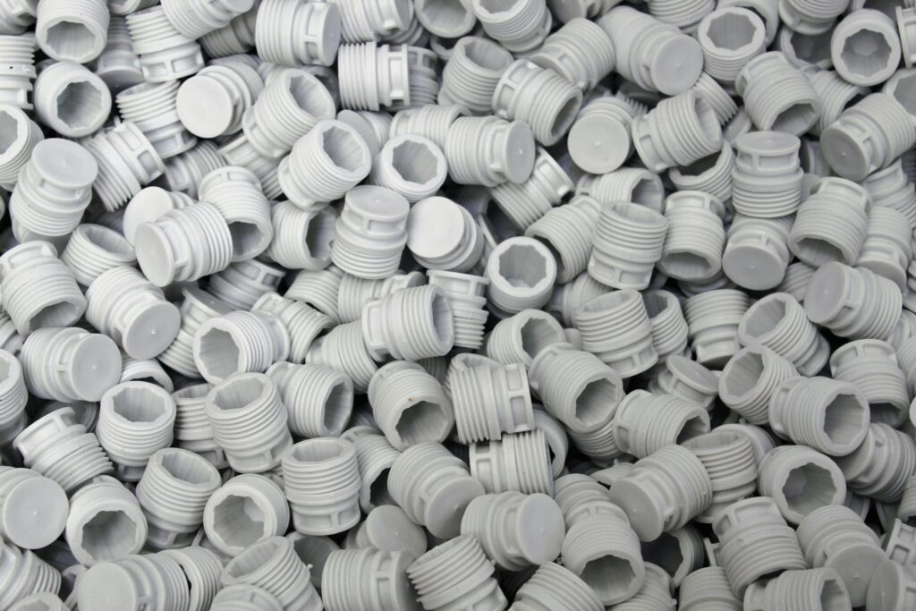 A high-quality image of numerous white plastic screw caps piled together, showcasing industry production.